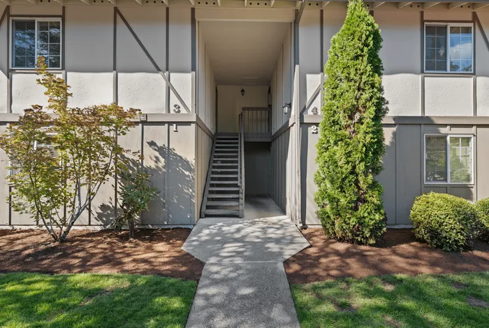 Charming apartment entrance surrounded by lush greenery and well-kept landscaping, offering a welcoming atmosphere.