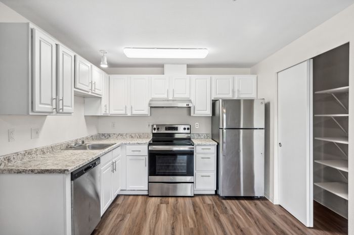 Modern kitchen with sleek stainless steel appliances, elegant white cabinetry, and granite countertops, ideal for culinary creativity.