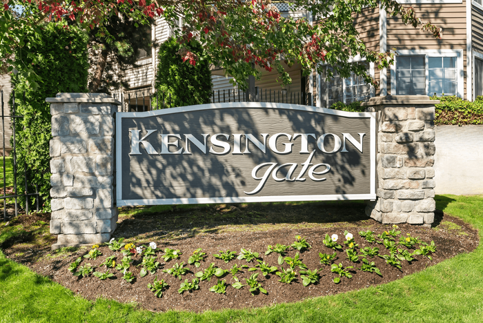 Inviting entrance sign for Kensington Gate, surrounded by lush greenery and elegant stone pillars, showcasing a welcoming and upscale residential community.