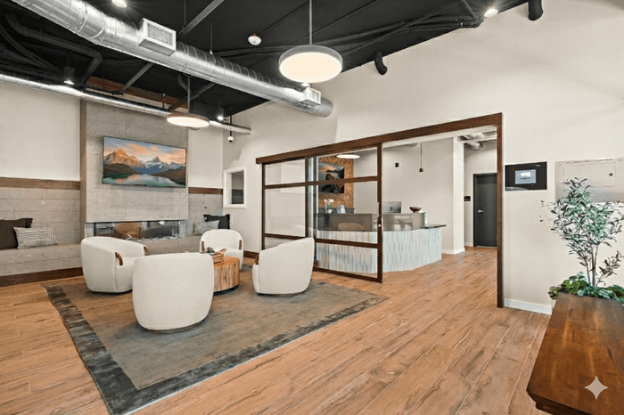 Modern lounge area featuring cozy seating, stylish decor, and an inviting reception desk with natural wood and light tones.