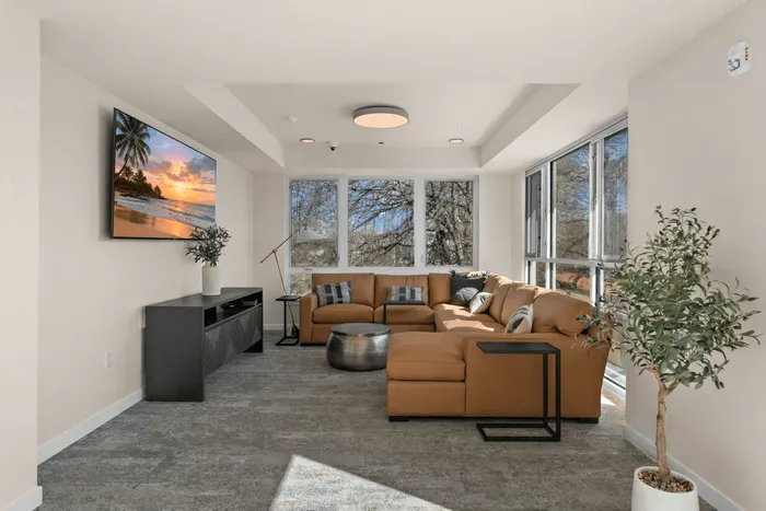 Contemporary living room with a cozy leather sectional, sleek entertainment unit, and expansive windows offering picturesque views.