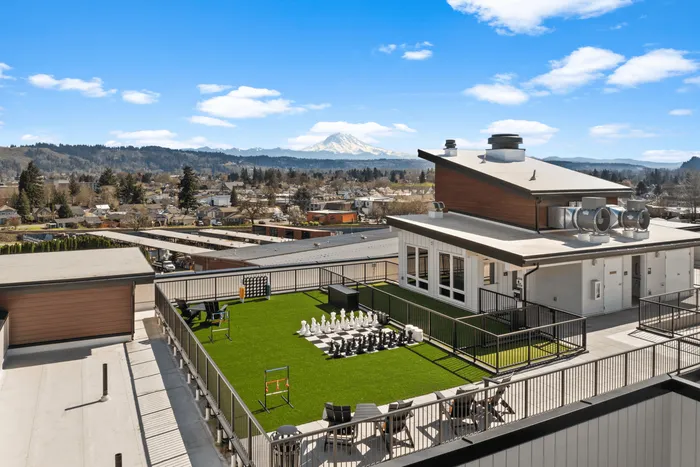 Stunning rooftop view featuring a vibrant green lawn with outdoor games, set against a backdrop of beautiful mountain scenery.