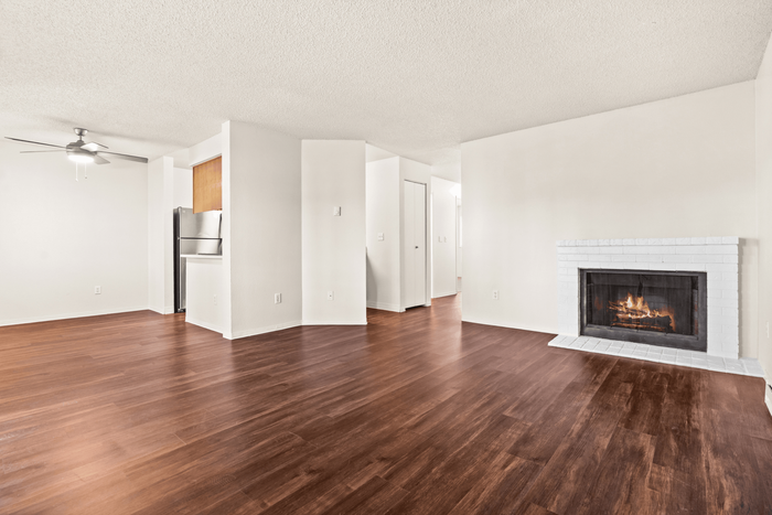 Inviting open-plan living area with sleek hardwood floors and a cozy fireplace, adjacent to a modern kitchen with stainless steel appliances.