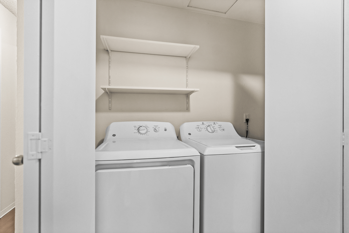 Modern laundry area featuring a sleek washer and dryer set with an overhead storage shelf, designed for convenience and efficiency.
