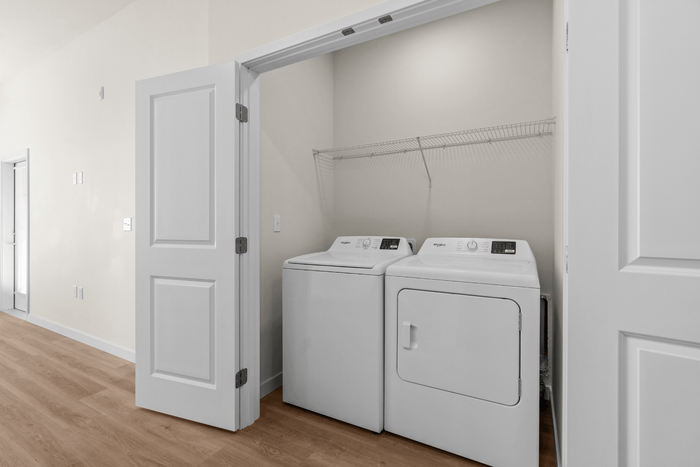 Modern laundry nook with washer and dryer, complete with sleek white doors and ample shelving.