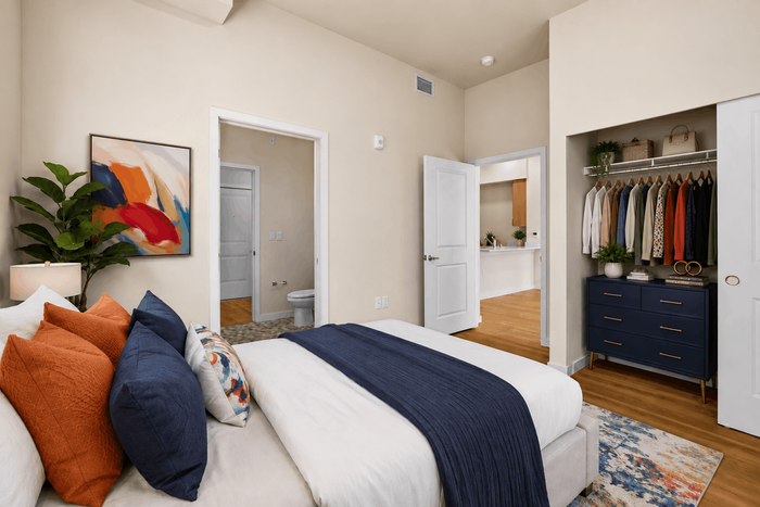 Inviting bedroom with modern decor, featuring a stylish navy dresser, spacious walk-in closet, and vibrant abstract wall art.