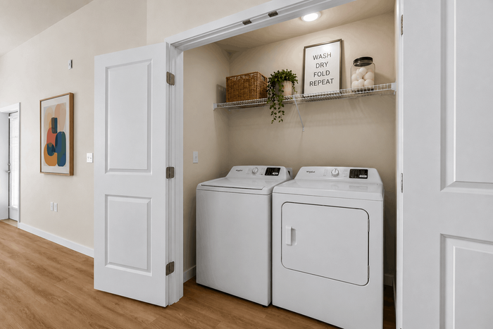Cozy laundry nook with modern washer and dryer units, accented by charming decor and natural wood flooring.