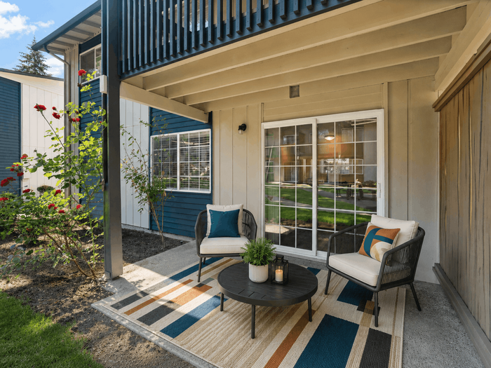 Charming patio with modern seating and vibrant rug, perfect for relaxing in a stylish, contemporary apartment courtyard.