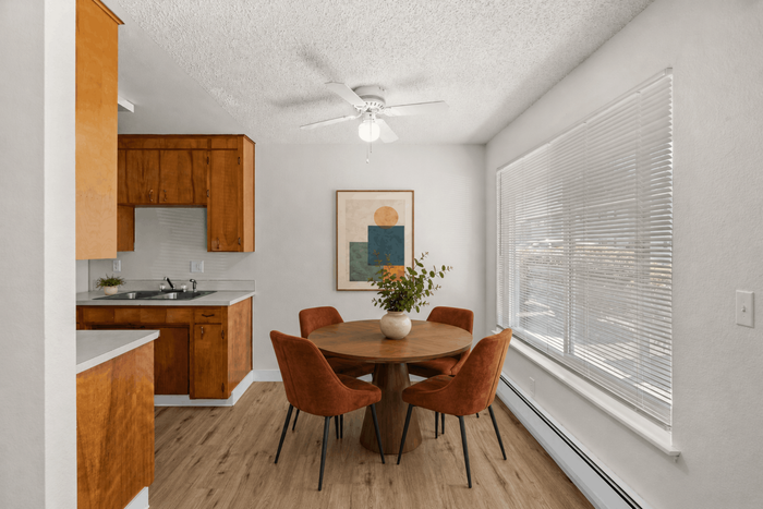 Bright dining area with modern round table and stylish chairs beside a contemporary kitchen, accented by large windows and elegant wooden flooring.