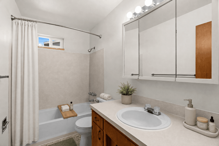 Bright modern bathroom featuring a sleek vanity, large mirror with elegant lighting, and a soothing bathtub with minimalist decor.