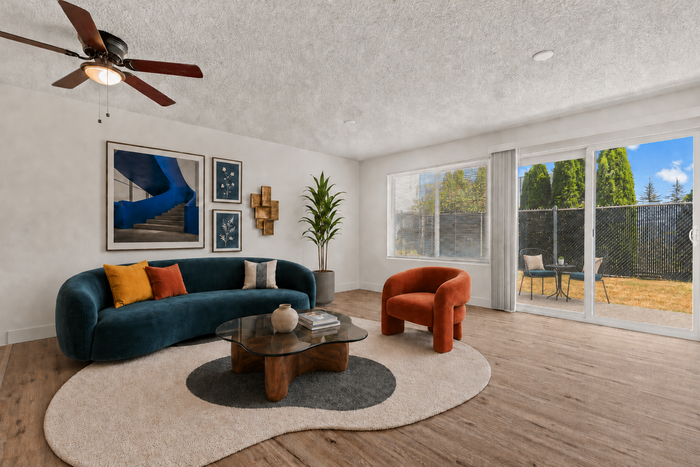 Chic living room with a modern teal sofa, vibrant cushions, artistic wall decor, and expansive sliding doors leading to a serene patio.