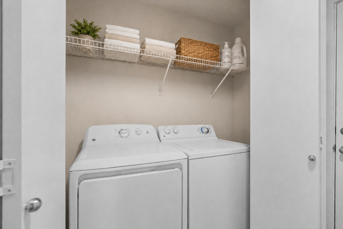 Chic laundry room featuring modern washer and dryer with ample shelving for storage in a cozy apartment setup.