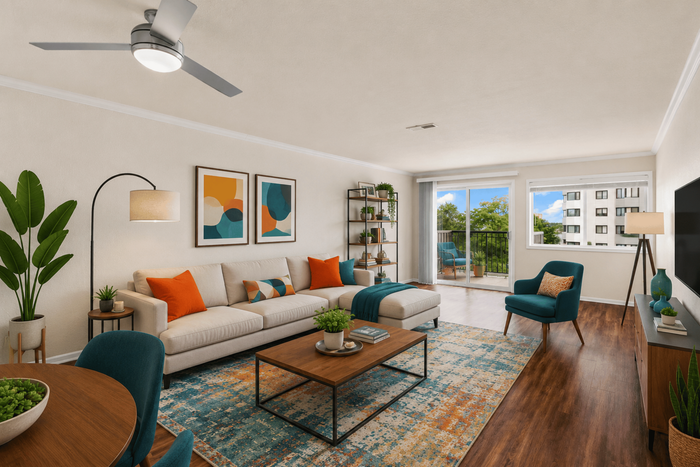 Bright, modern living room with chic decor, featuring a plush beige sofa with colorful cushions, vibrant artwork, and large window offering stunning urban views.