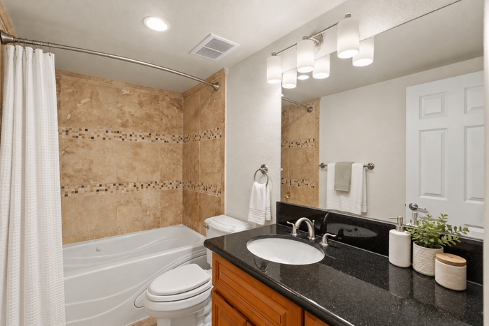Elegant bathroom with sleek granite countertop, stylish vanity mirror, and a relaxing bathtub with modern tile accents.