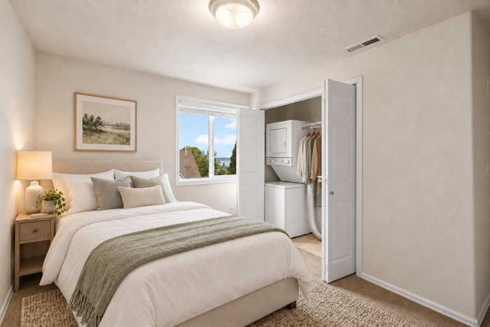 Bright and cozy bedroom featuring a plush bed, elegant decor, and convenient in-room laundry facilities with natural light streaming through the window.