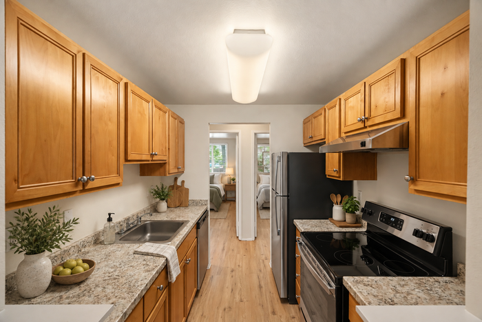 Charming kitchen with warm wooden cabinetry, sleek stainless steel appliances, and elegant granite countertops, leading into a cozy room with a soft glow.