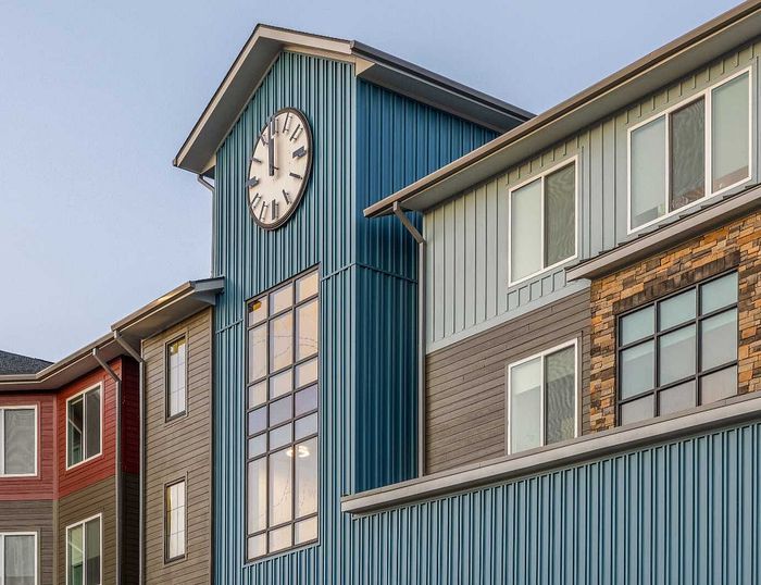 Contemporary apartment building facade with a large clock tower and modern window design.