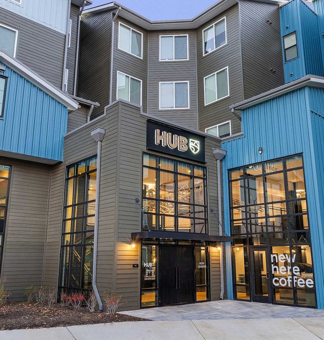 Modern urban apartment building with striking architecture, featuring HUB logo and stylish glass frontage in a vibrant neighborhood.