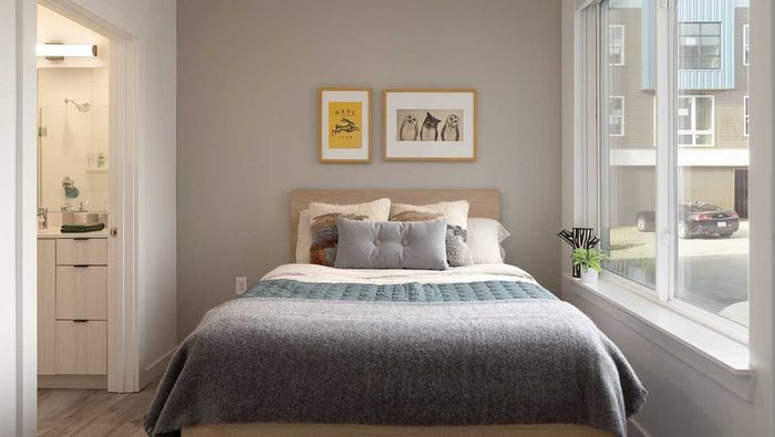 Bright and cozy bedroom with large window, stylish decor, and en-suite bathroom access.