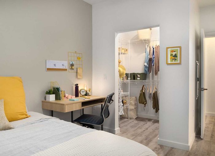 Cozy bedroom with modern built-in desk and walk-in closet featuring stylish shelving and ample storage space.