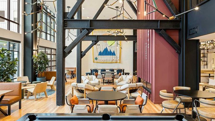 Chic and modern communal seating area with vibrant art, stylish lighting, and comfortable chairs, perfect for social gatherings.
