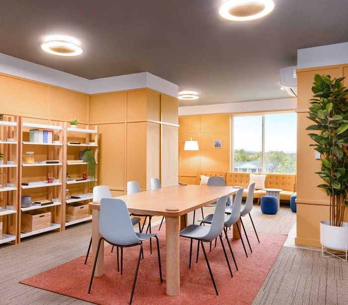 Modern and inviting communal space with a large wooden table, stylish chairs, and cozy seating area filled with natural light.
