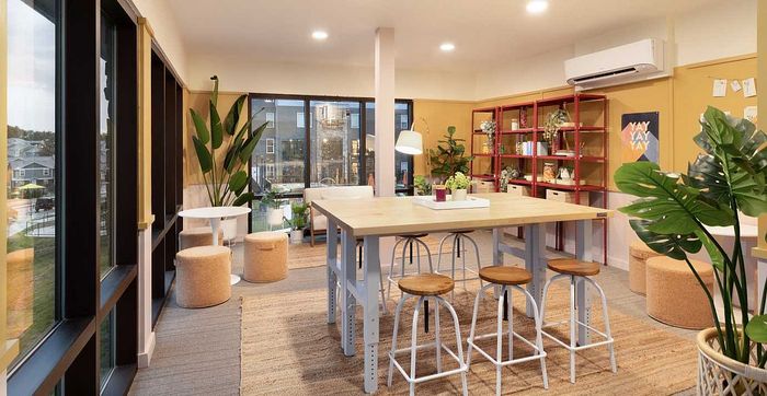Charming communal space with modern decor, featuring a large dining table, cozy seating, and abundant natural light through large windows.