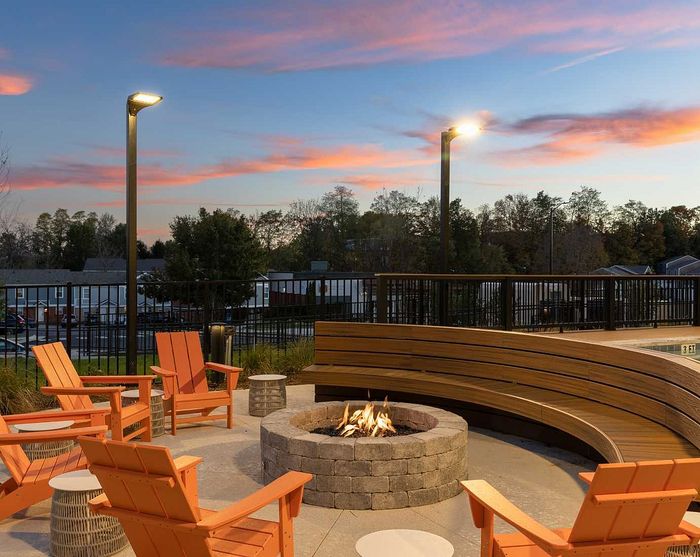 Inviting outdoor seating area with cozy fire pit, surrounded by stylish chairs and elegant sunset views.