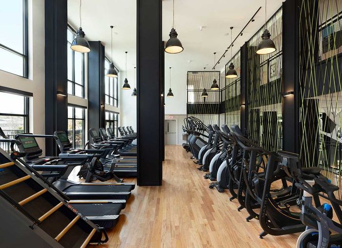Modern fitness center with large windows, trendy lighting, and state-of-the-art equipment, including treadmills and ellipticals.