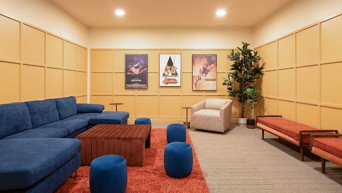 Chic apartment lounge with a plush blue sectional, vibrant orange rug, and stylish wall art creating a cozy atmosphere.