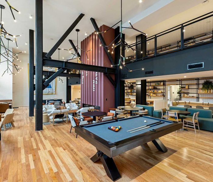 Modern recreational space featuring a stylish billiards table, chic seating, and contemporary lighting in an open-concept lounge area.