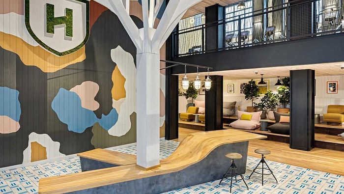 Vibrant and modern coworking space featuring colorful wall designs, stylish seating, and a unique wave-shaped wooden table.