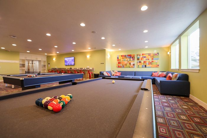 Elegant game room with pool tables, colorful seating, and contemporary art.