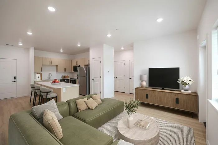 Modern open-concept living area with stylish kitchen, cozy green sofa, and elegant decor, perfect for entertaining.