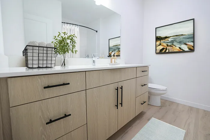 Modern bathroom featuring sleek wood cabinetry, elegant countertop, and stylish decor with a coastal painting.