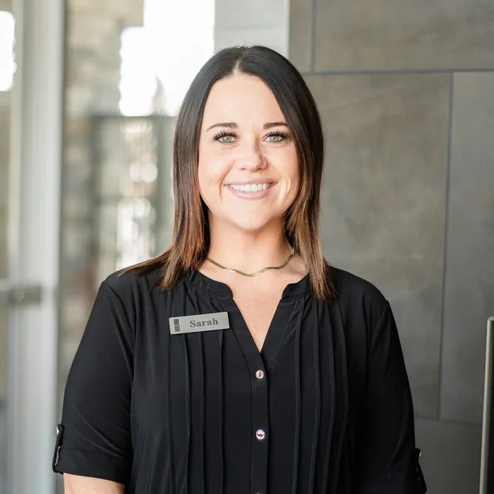 Friendly real estate agent standing in a modern, stylish interior with a welcoming smile and professional attire.