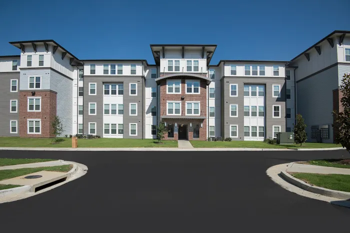 Elegant modern apartment building with a sleek facade, featuring large windows and a well-maintained lawn in a serene neighborhood.