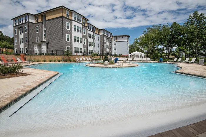Luxurious apartment complex with a stunning resort-style swimming pool, surrounded by stylish lounge chairs, perfect for relaxation and leisure.