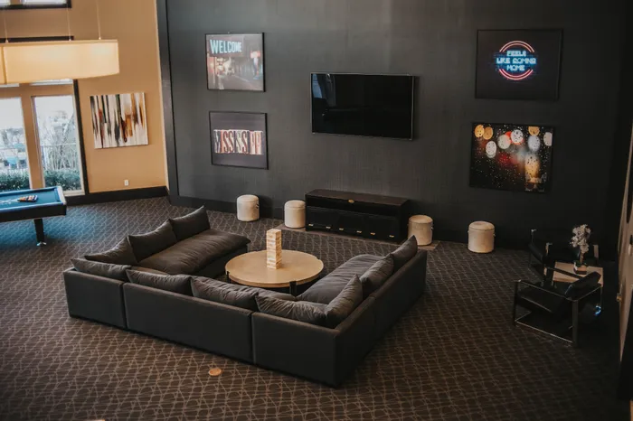 Chic and inviting lounge area with plush sectional sofa, stylish artwork, and modern game table for entertaining.