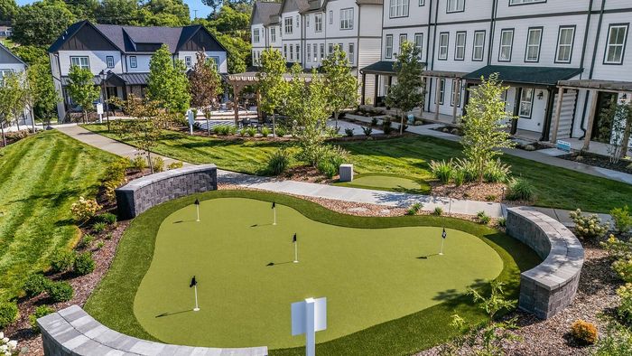 Charming residential area featuring modern townhouses, lush landscaping, and a well-maintained mini golf putting green for leisure and relaxation.