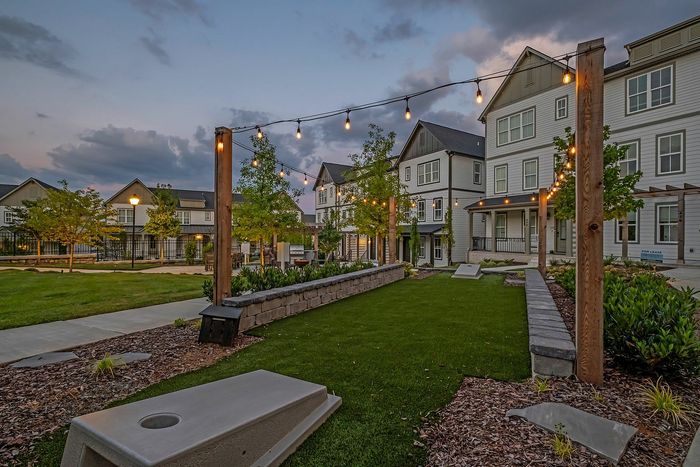 Charming residential community with beautiful townhomes featuring twilight ambiance, landscaped grounds, and inviting outdoor lighting.