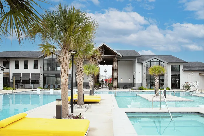 Resort-style pool deck with palm trees at Wildwood Baton Rouge student apartments near LSU