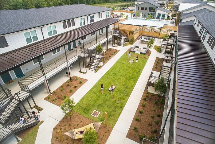 Central courtyard lawn with hammock and outdoor games at Wildwood Baton Rouge student apartments near LSU