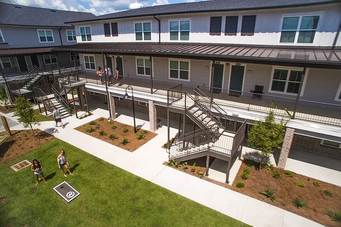 Students walking through landscaped courtyard and breezeway at Wildwood Baton Rouge student apartments near LSU