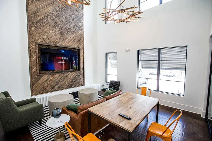 Cozy clubhouse media lounge with fireplace wall, seating and communal table at Wildwood Baton Rouge student apartments near LSU