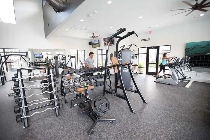 Students using weights and cardio equipment in the fitness center at Wildwood Baton Rouge student apartments near LSU