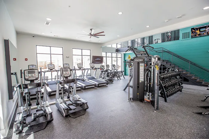 Modern fitness center with cardio machines and weights at Wildwood Baton Rouge student apartments near LSU