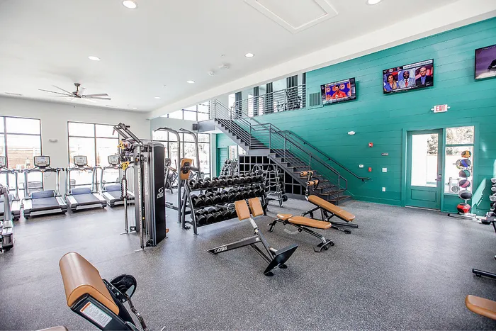 Spacious fitness center with weights, benches and cardio machines at Wildwood Baton Rouge student apartments near LSU
