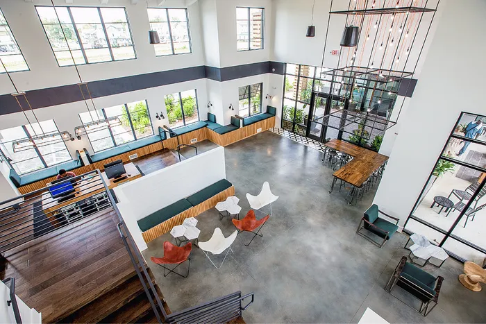 Spacious two-story clubhouse lounge with seating, study areas and communal tables at Wildwood Baton Rouge student apartments near LSU