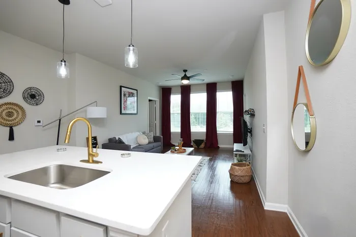 Elegant modern apartment with a stylish open-plan living area, sleek kitchen island, and luxurious decor featuring warm lighting and hardwood floors.